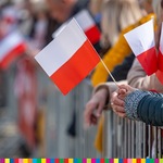 Polskie flagi w dłoniach.