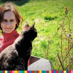 Kobieta i czarny kot na tle zielonej trawy