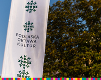 Biały baner z napisem: Podlaska Oktawa Kultur, w tle niebo, po prawej stronie drzewa