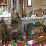 Ołtarz w kościele, po prawej stronie ksiądz przemawia na ambonie, pod ołtarzem stoją wieńce dożynkowe 