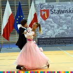 Para ubrana w elegancki ubiór tańczy. W tle flagi biało-czerwone i unijna