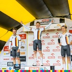 Trzej mężczyźni w barwach narodowych Niemiec stoją na najwyższym stopniu podium