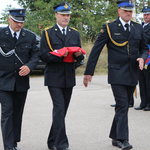 Trzej mężczyźni w mundurach niosą flagę Polski