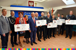 Wicemarszałek Olbryś wraz z przedstawicielami samorządu oraz przedstawicielami OSP trzymającymi w rękach symboliczne czeki.