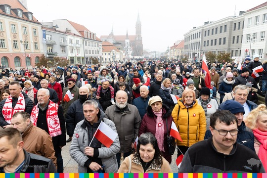 Tłum ludzi zebrani na placu w centrum Białegostoku. Trzymają w ręku flagi biało-czerwone