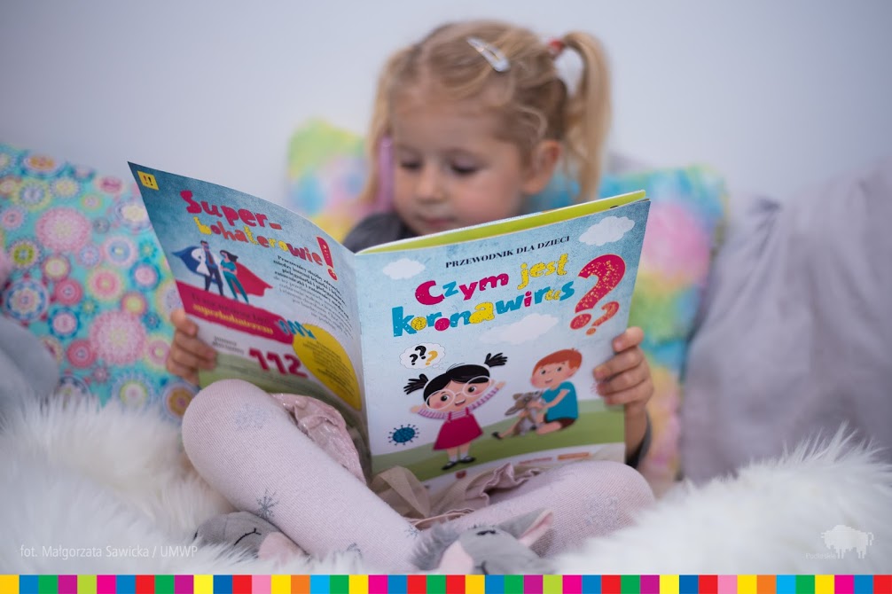 Dziewczynka czytająca książeczkę: Czym jest koronawirus?
